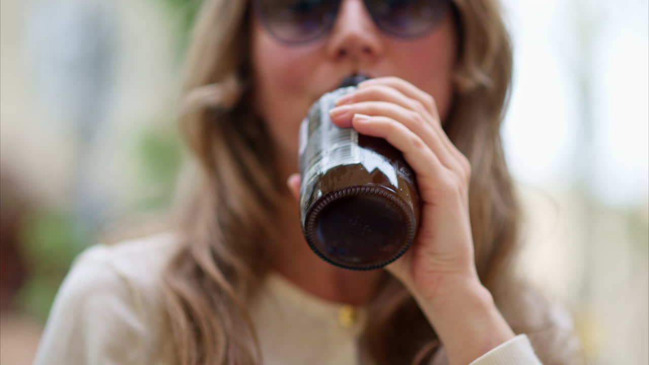 Close-up of brunette, young woman drinking a kombucha tea outside