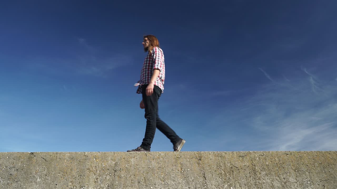파란 하늘 4k에 대항하여 돌 벽에 편안하게 는 남자