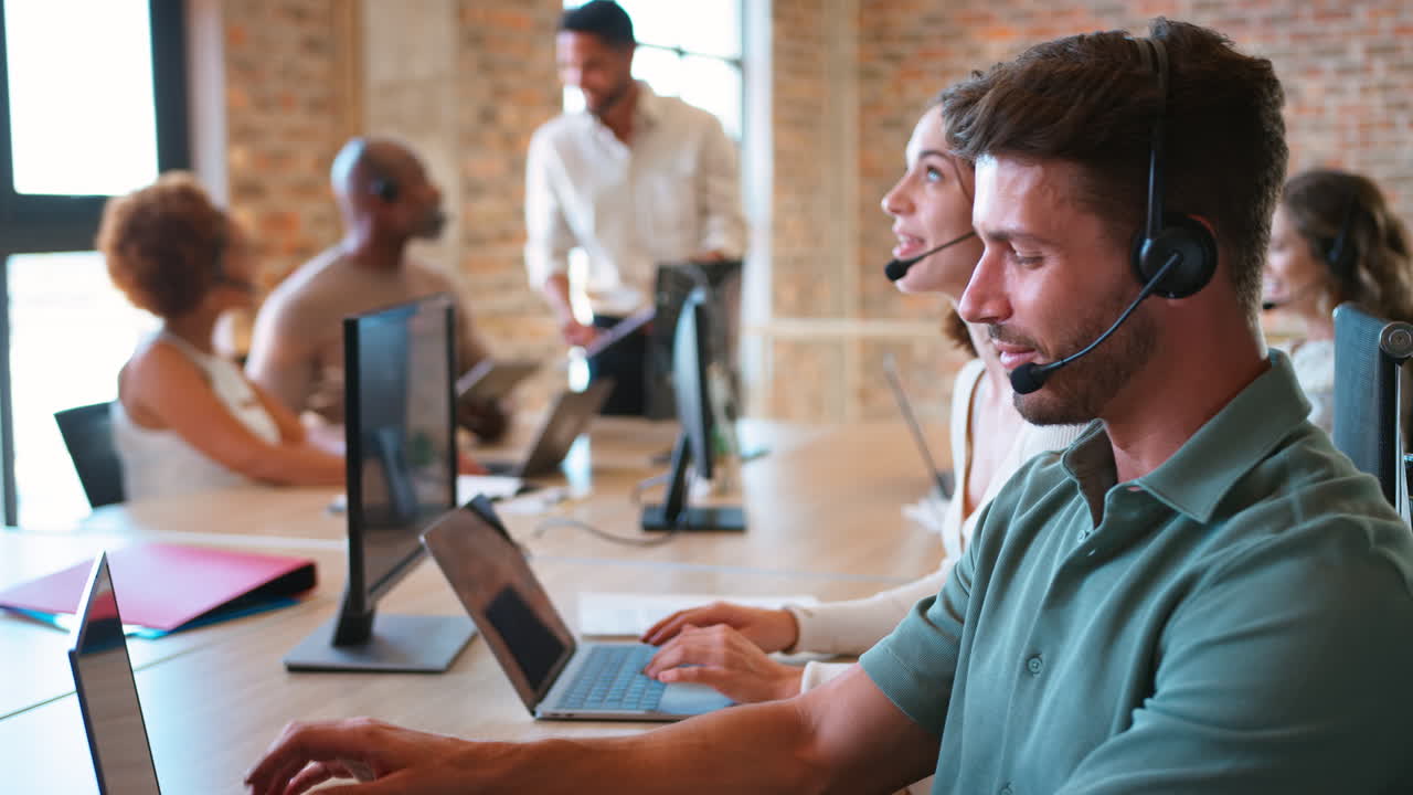 Portrait Of Businessman In Multi-Cultural Business Team Wearing Headset In Customer Support Centre