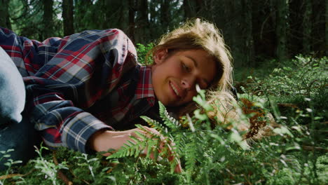 tourist relaxing on grass in summer forest. young woman lying on ground in woods