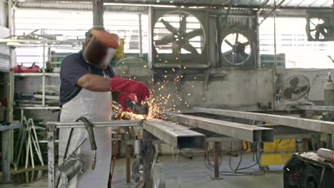 slow motion of a worker using metal grinder with sparks flying at a metal shop