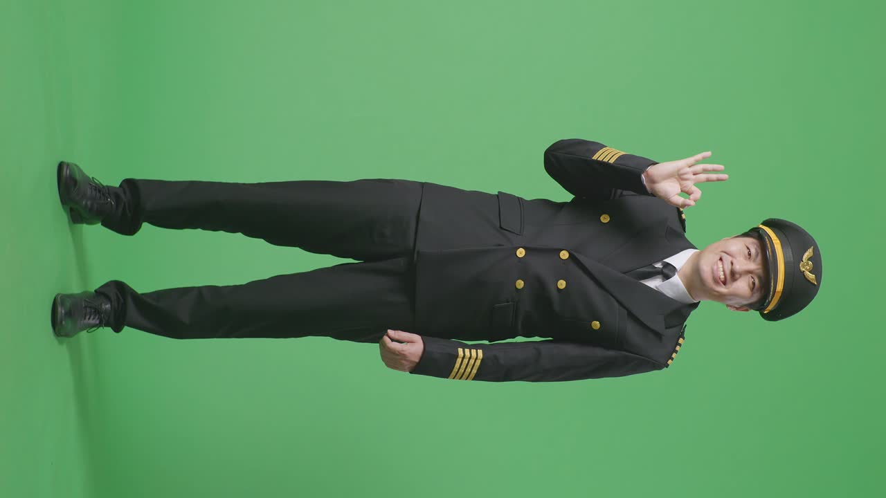 полное тело азиатского мужчины пилот улыбается и показывает хорошо жест к камере в то время как стоит в зеленом экране фоновой студии