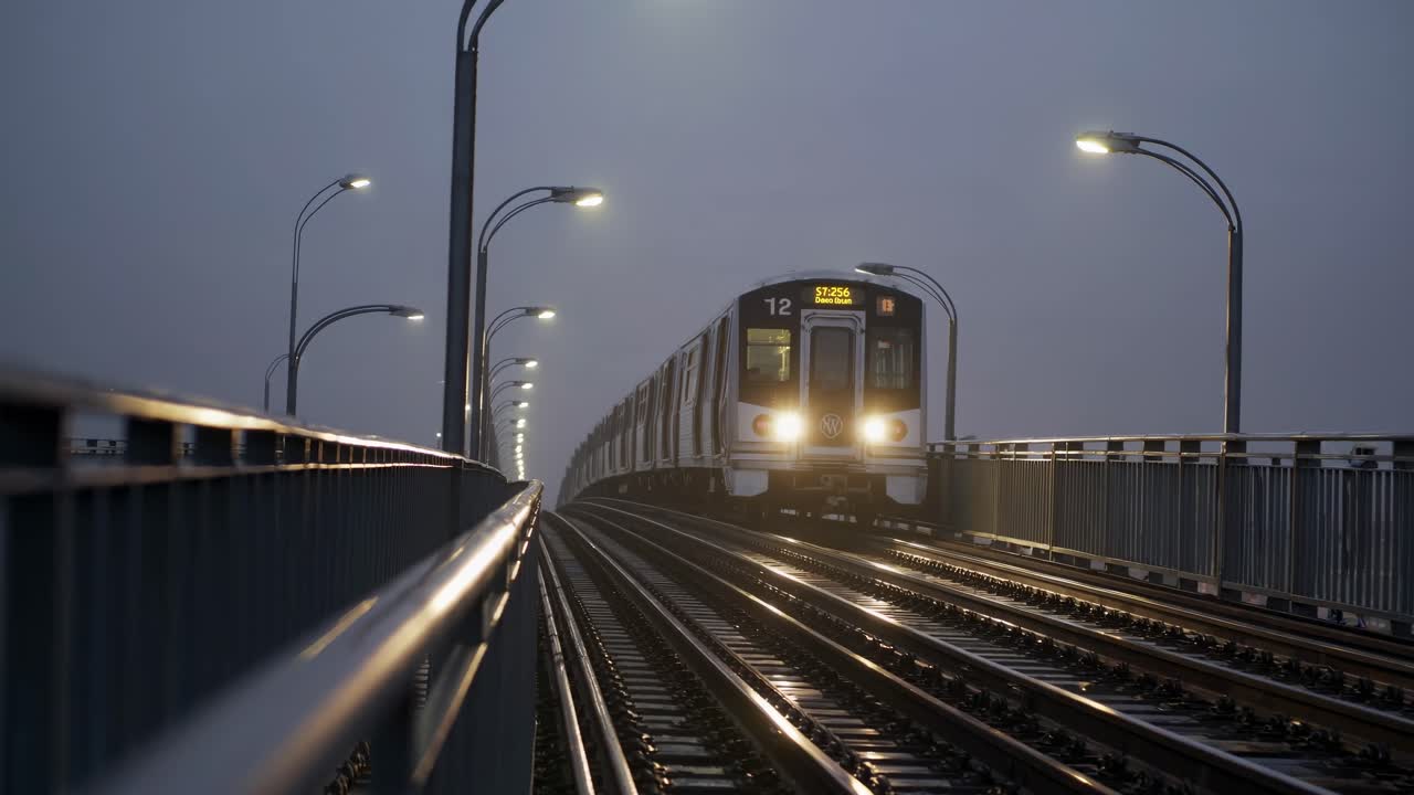 Dramatic video still of a train approaching on a foggy bridge, captured from a low angle