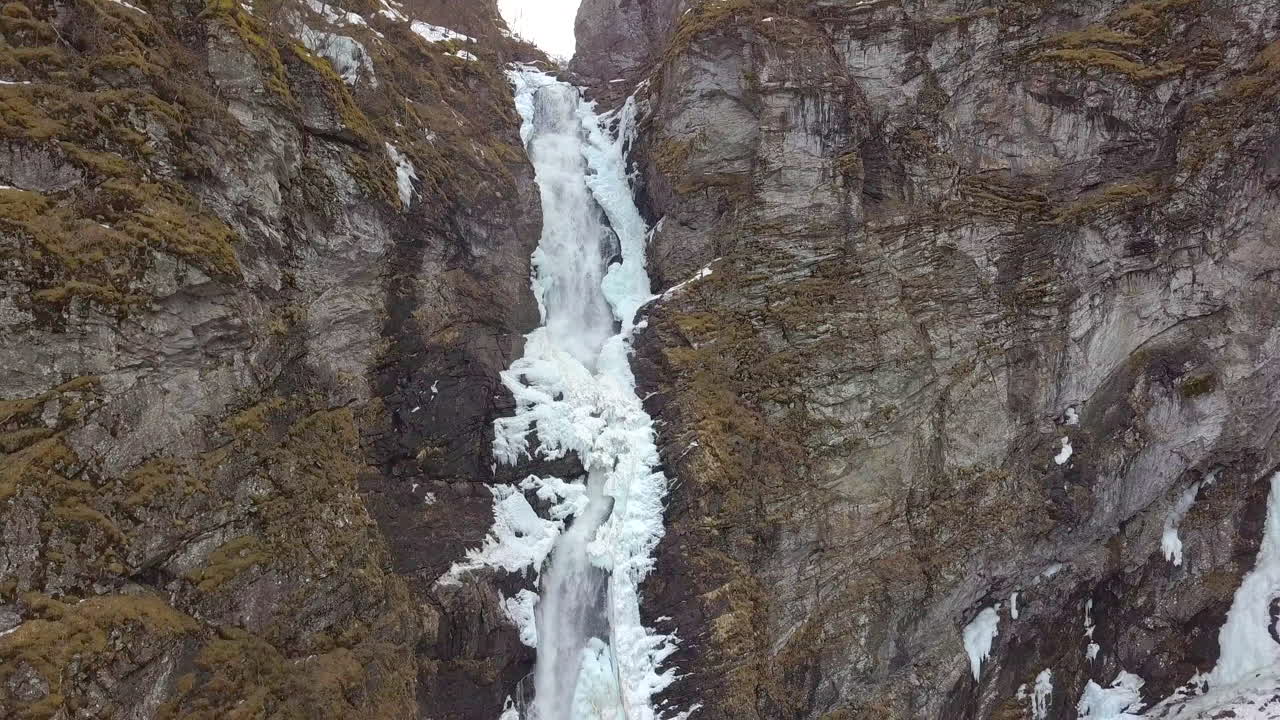 Veduta aerea di una cascata ghiacciata che si fa strada attraverso una scogliera in Norvegia, con movimento in lenta discesa.