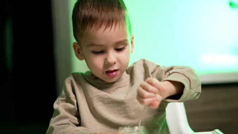 cute adorable baby boy with some dairy on his face. happy toddler kid eating yogurt. close up.