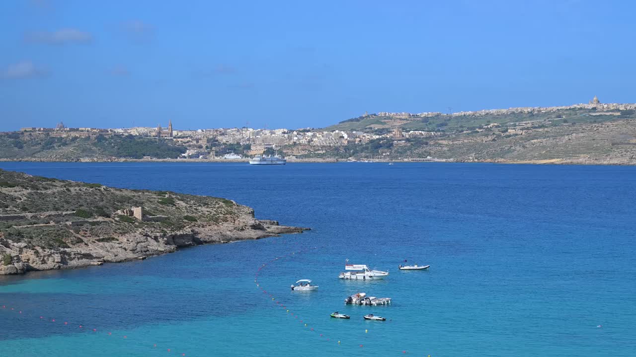 A stunning view from Comino towards Malta, showcasing turquoise waters, rocky cliffs, and the natural beauty of the Mediterranean landscape