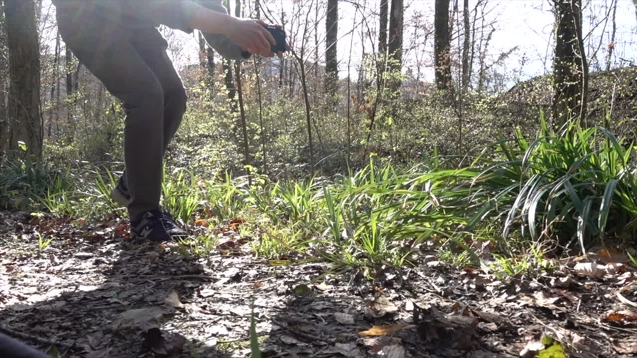 caminata ninja de un cineasta en un bosque, capturando imágenes fluidas, cámara en mano