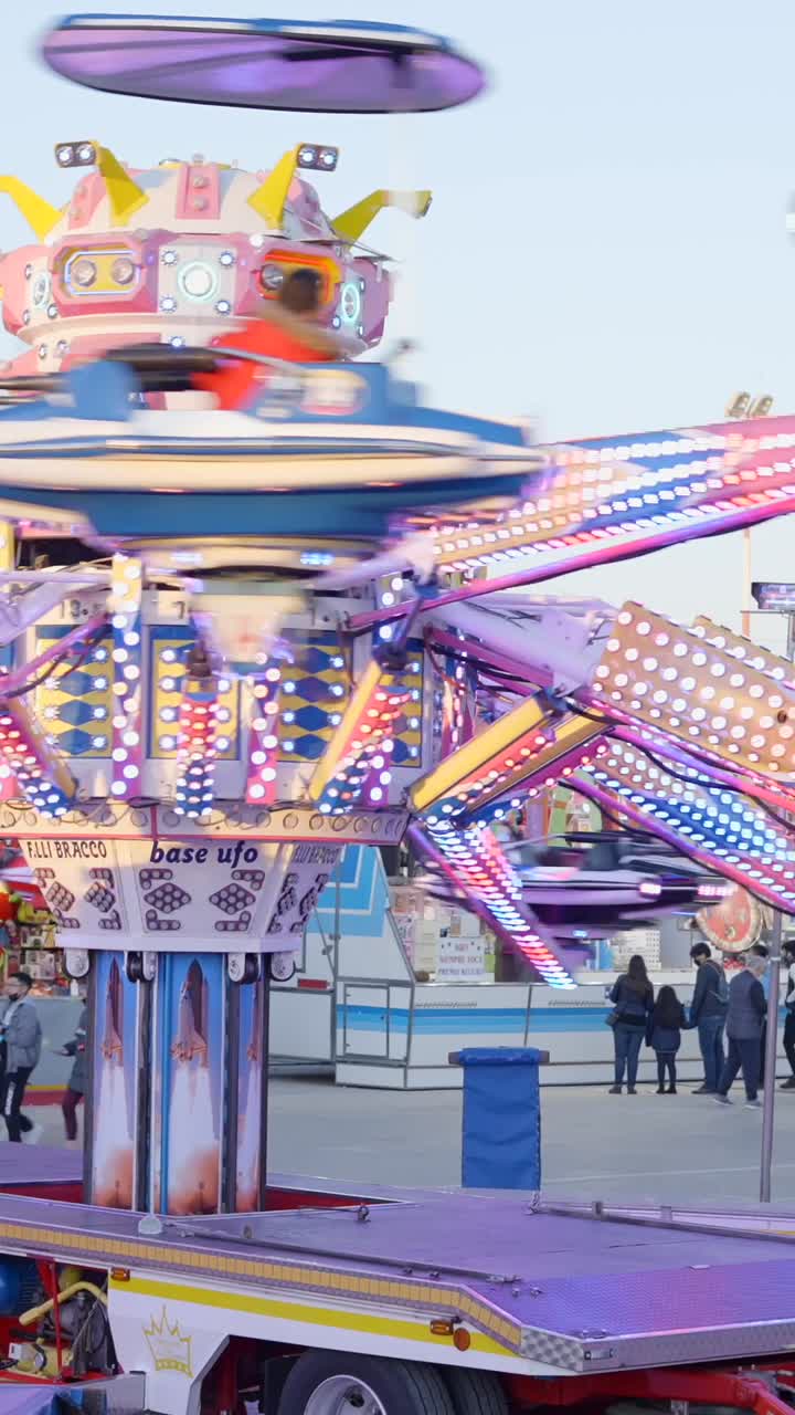 A brightly lit, colorful amusement park ride in motion