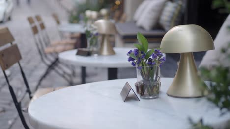 a table set with flowers and a lamp outside a cafe