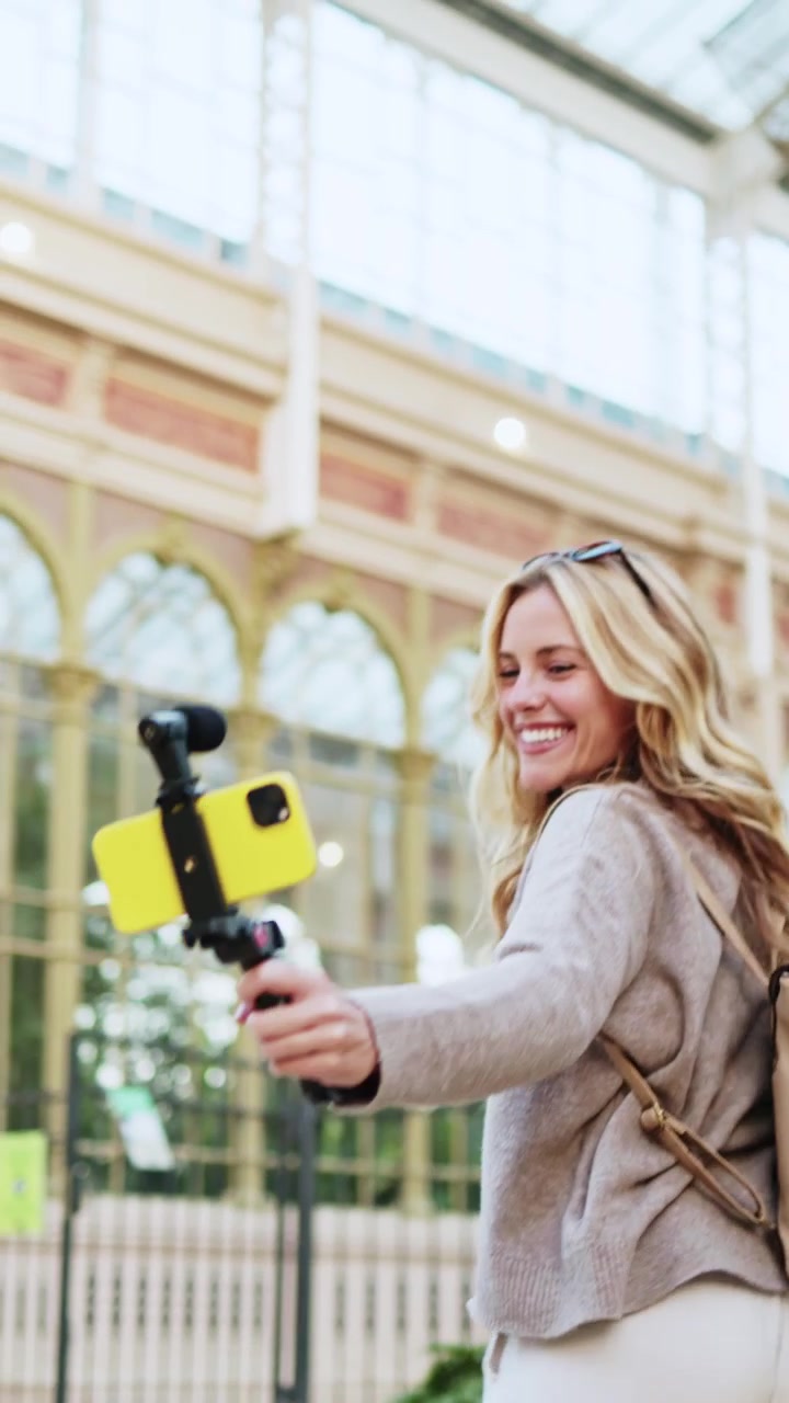 Giovane donna felice che fa vlogging con smartphone e gimbal all'aperto