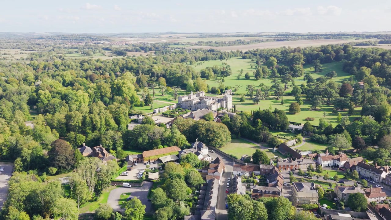Aerial view of Wilton House in Wiltshire surrounded by landscaped parkland mature trees historic buildings and rolling English countryside