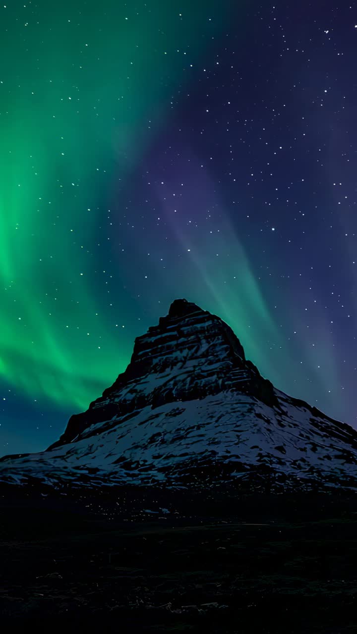 Vertical video: Emerging green auroral band on left horizon, moving over snowy mountain at night