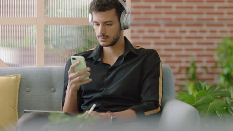 young hispanic man using digital tablet computer drawing browsing online sharing social media messages student sketching enjoying listening to music checking smartphone in modern office