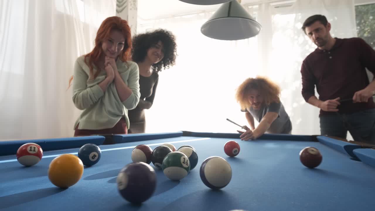 Man playing pool with friends in game room at home