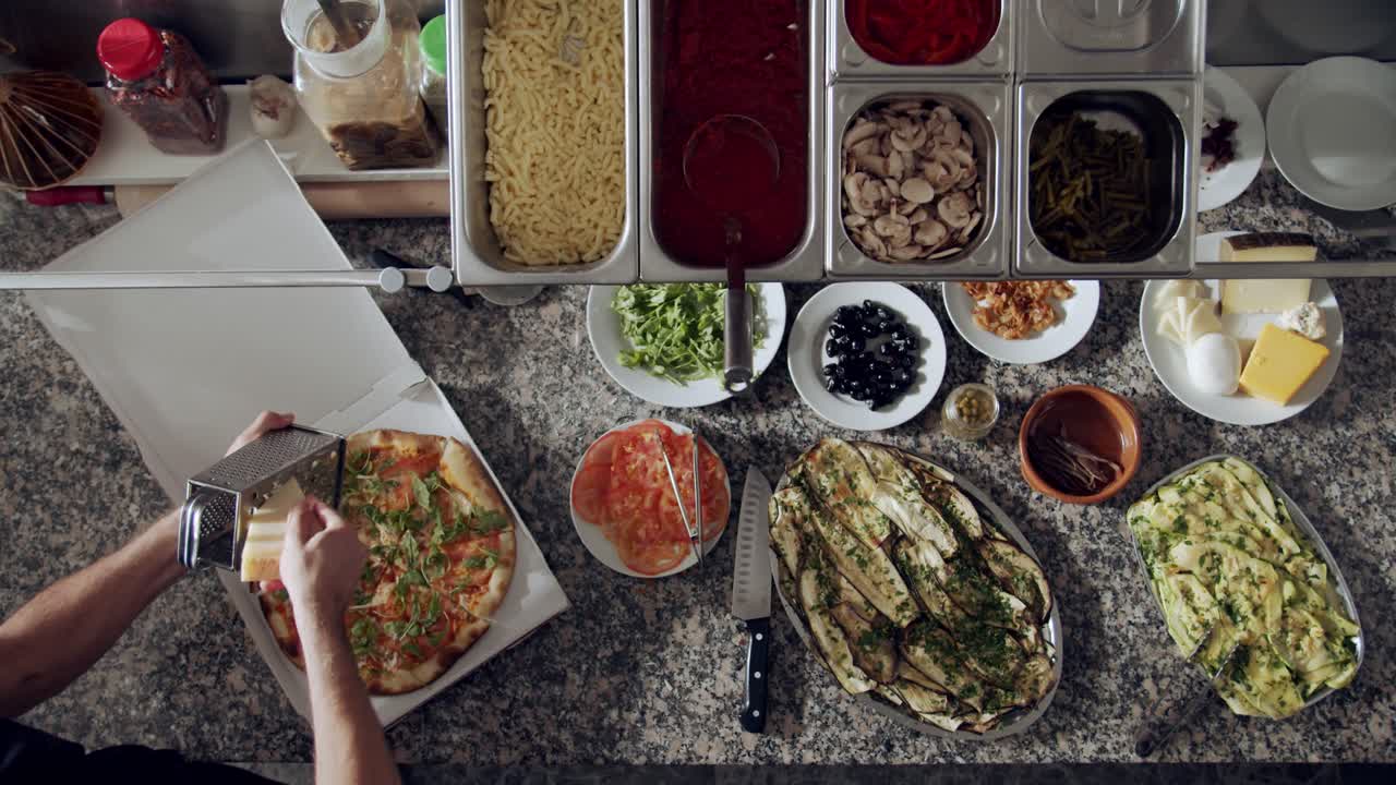 피자이올로 (pizzaiolo) 는 구운 피자 위에 치즈를  ⁇ 는다.