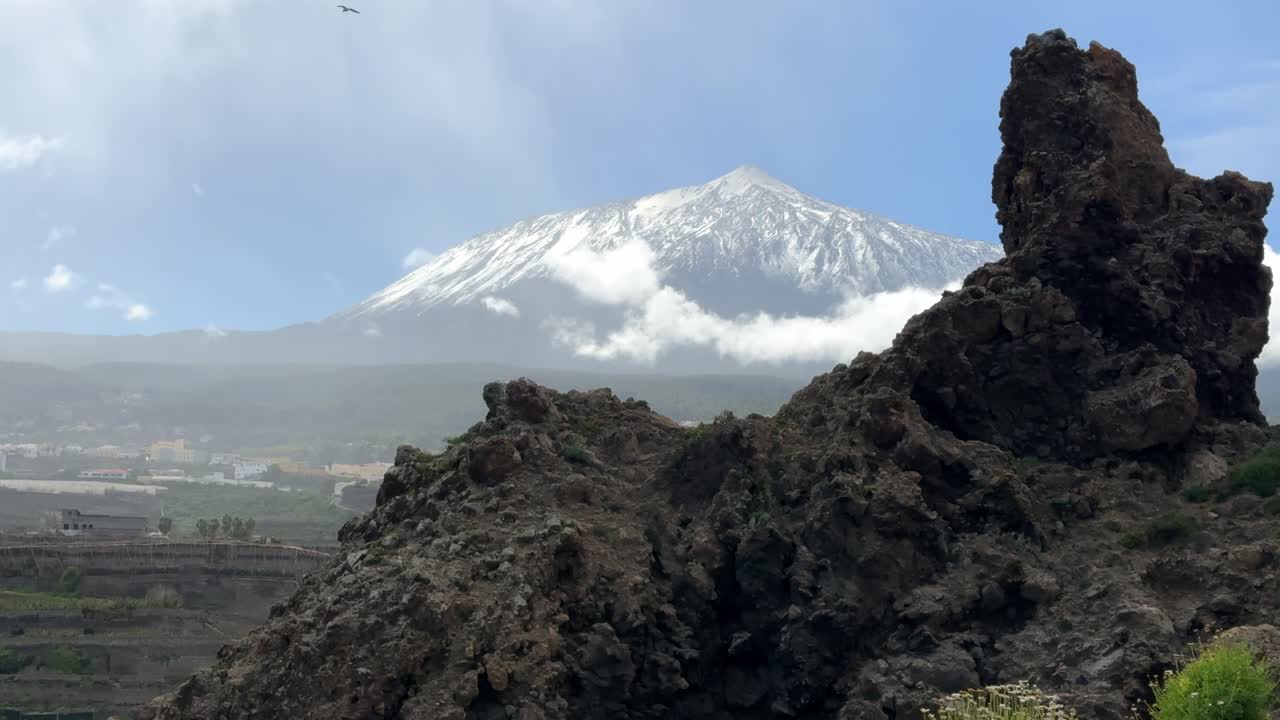Vista maestosa della cima innevata del vulcano Teide in una giornata di sole. Formazioni rocciose vulcaniche in primo piano a Tenerife.