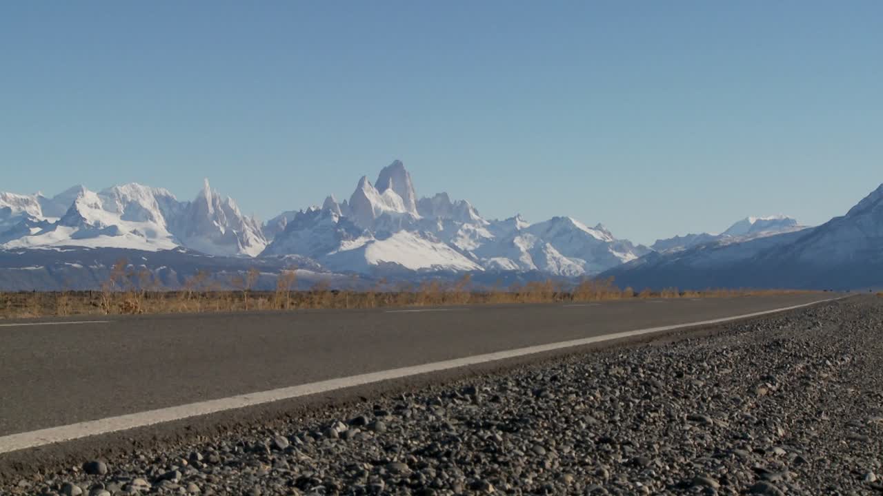 un camion passa su un'autostrada remota nel sud dell'argentina con la catena montuosa fitzroy sullo sfondo della patagonia