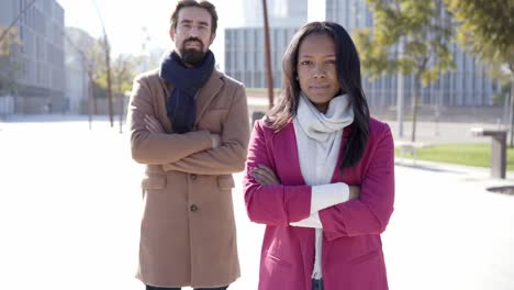 portrait of a serious business people crossing arms and looking at the camera standing outdoors in a financial center in a city.