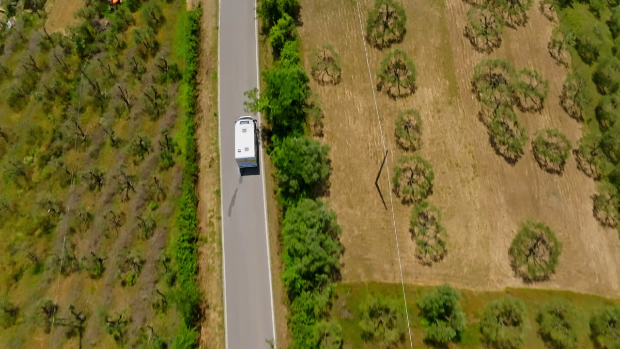 High angle drone shot following a RV driving through a Tuscan town in Italy