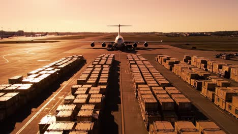 an aircraft is stationed on the runway at a major airport as sunset casts a golden hue over the scene. cargo containers fill the area, indicating bustling activity.