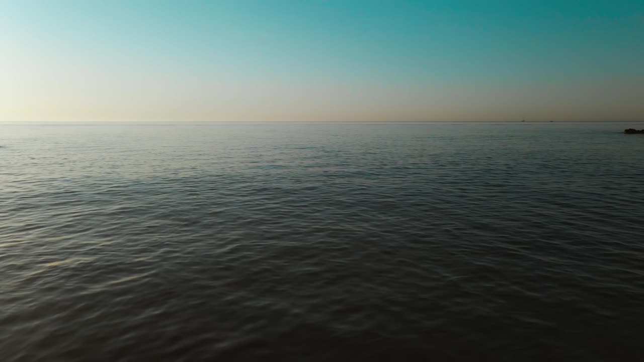 Fly over gentle waves at Fuengirola beach during sunset, South of Spain