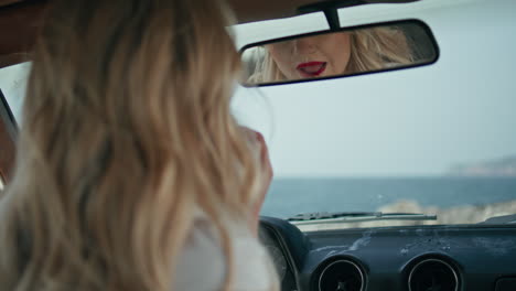 gorgeous woman applying lipstick looking in car mirror close up. lips makeup