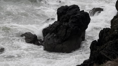 rough autumn tide crashes in on dark rocks in the small village of port patrick, dumfries and galloway, scotland