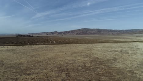 Drohnenaufnahme-Einer-Großen-Rasenfläche-In-Zentralkalifornien-Mit-Einem-Feld-Und-Bergen-Im-Hintergrund