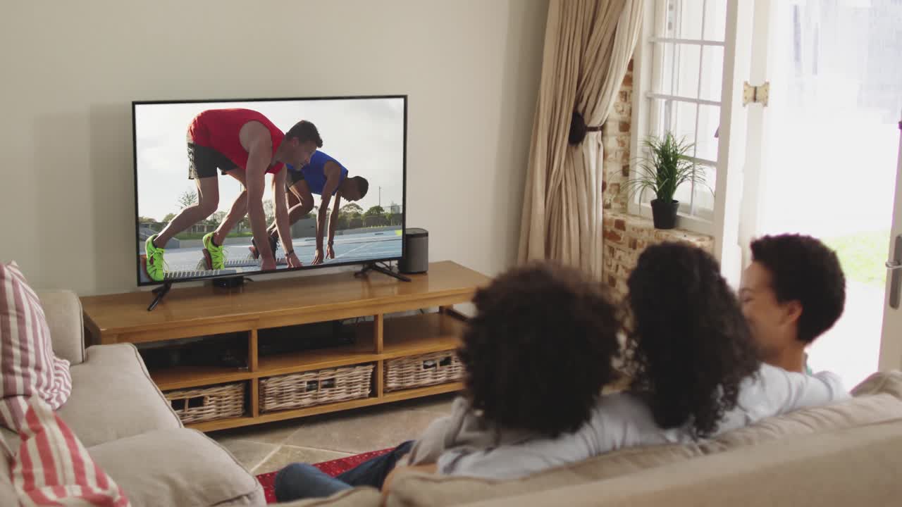 Composizione di famiglia felice seduta insieme a casa che guarda un evento di atletica leggera di corsa in TV.