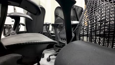 discarded office chairs are seen piled up in a basement storage room, representing concepts of waste, obsolescence, and office furniture disposal