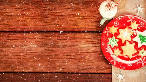 galletas de navidad y bebida caliente en madera combinada con la nieve que cae