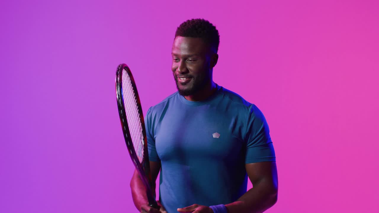 Video di un felice giocatore di tennis afroamericano sotto luci rosa neon a forma di fulmine.