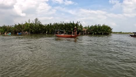 Fisherman-casting-net-from-a-small-boat-on-Thu-Bon-river,-Vietnam