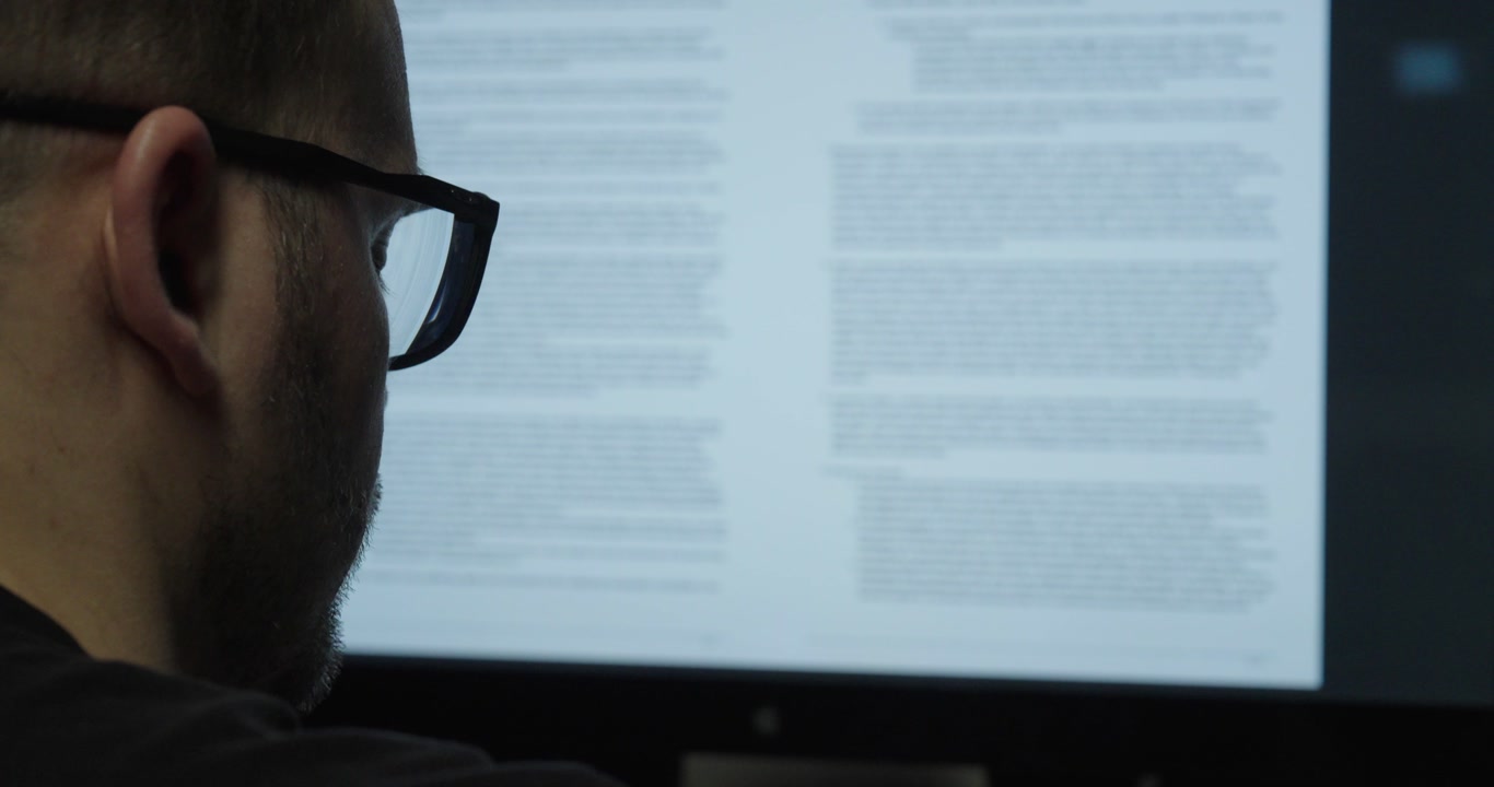 Man carefully reviewing contract terms on a computer screen. Concept of legal analysis, business agreement and document check.