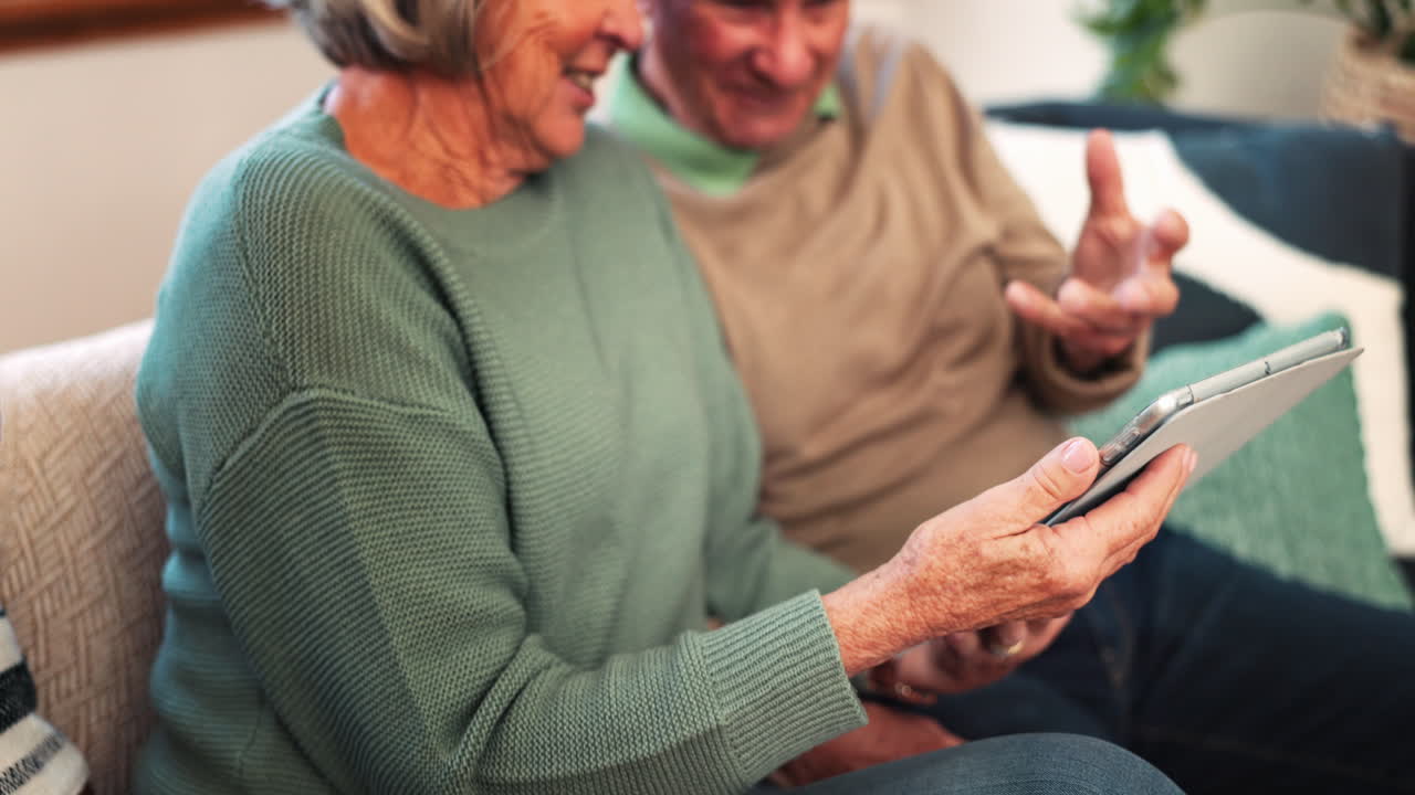 Coppia anziana, mani e tablet a casa