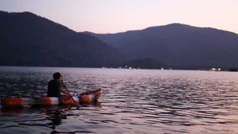 two people kayaking on a calm lake at sunset