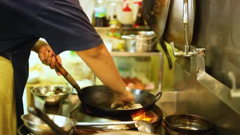 chef skillfully cooks with a wok in kitchen