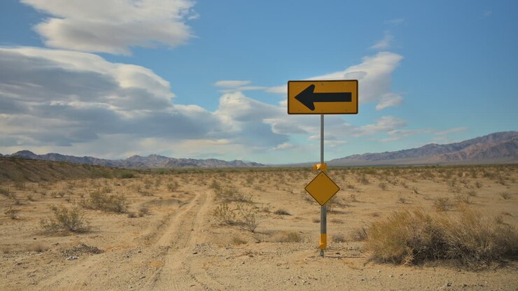 Cartello con freccia che indica la direzione dell'autostrada nel deserto della California.