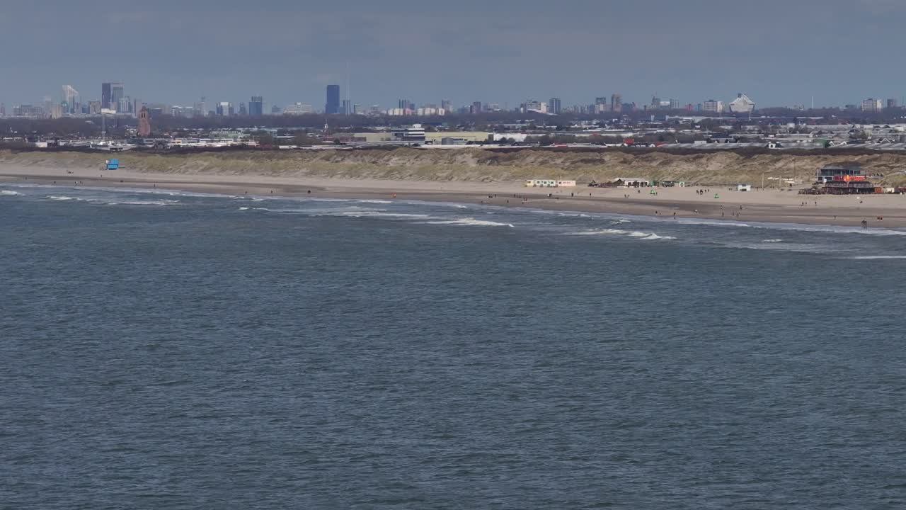 hoek van holland playa, los países bajos - olas blancas chocan contra la costa prístina de la playa - toma amplia