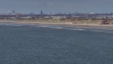 hoek van holland beach, the netherlands - white waves crash onto the pristine beach shoreline - wide shot