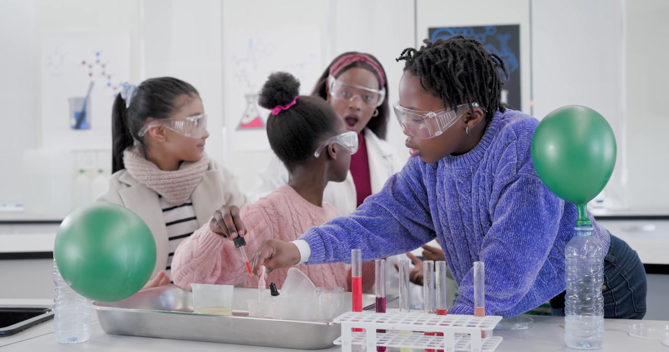Öğretmenin laboratuvar tezgahında deney tüplerine pipetle sıvı aktararak buharı gözlemlemeye yönlendirdiği Afro-Amerikalı çocuklar.