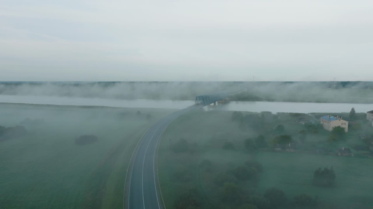 ⁇ 은 여름 아침에 젤루페 강을 가로지르는 철강 다리의 공중 뷰, 강 위로 떠오르는 안개, 자동차 운전, 넓은 드론  ⁇ 이 낮게 앞으로 이동