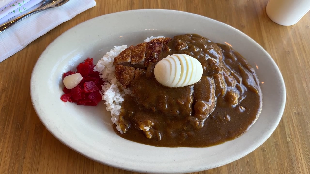 白いご飯、輪切りのゆで卵、福神漬けと共に木製テーブルに盛り付けられた、レストランのランチやディナー向けの伝統的な日本のチキンカツカレーのプレート