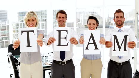 business people holding pages spelling out team