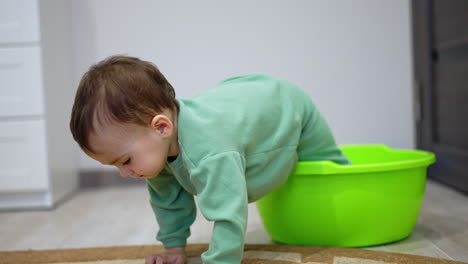 baby playing with a green basin