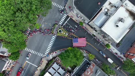 the crowd at an intersection as floats and a giant star-spangled banner pass by