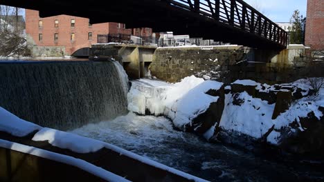 wide angle view of dam with ice and rocks and bridge