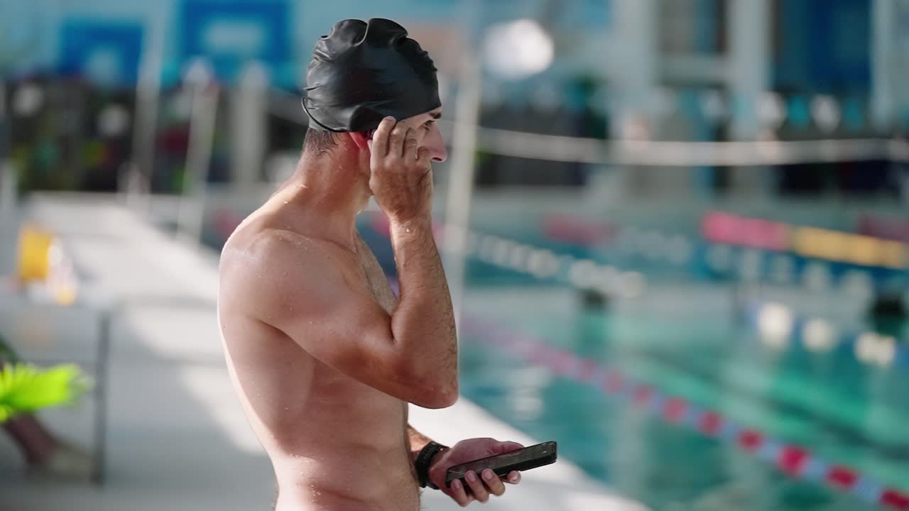 Uomo con cuffia da nuoto che ascolta un audio a bordo piscina