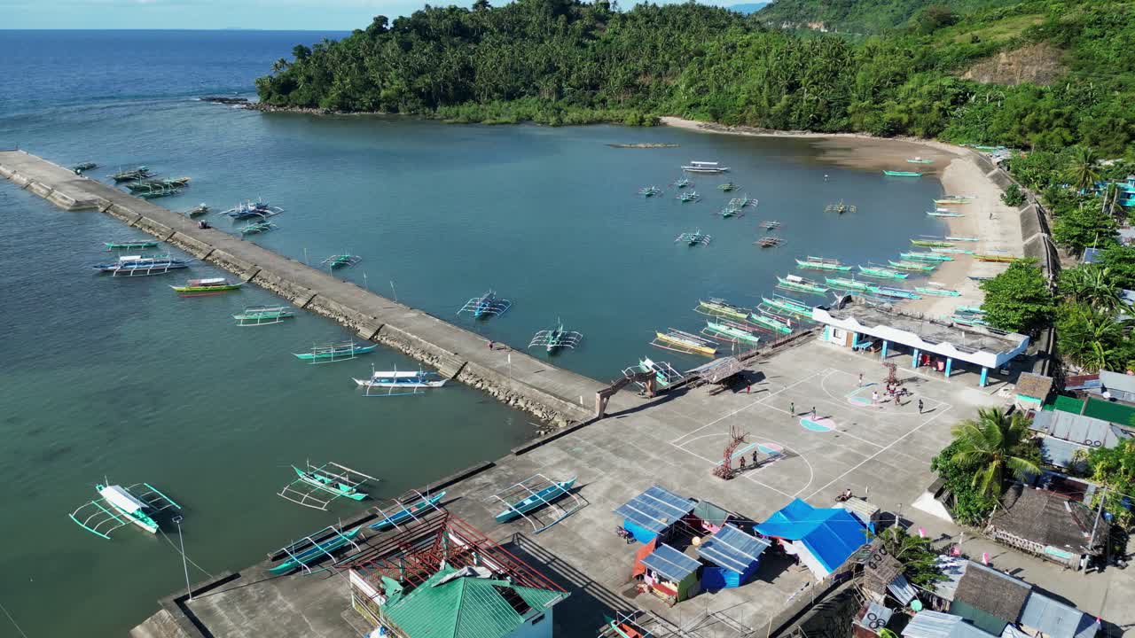 Idyllic Flyover Shot of a Quaint Coastal Village Town facing lagoon and dock with traditional bangka boats anchored