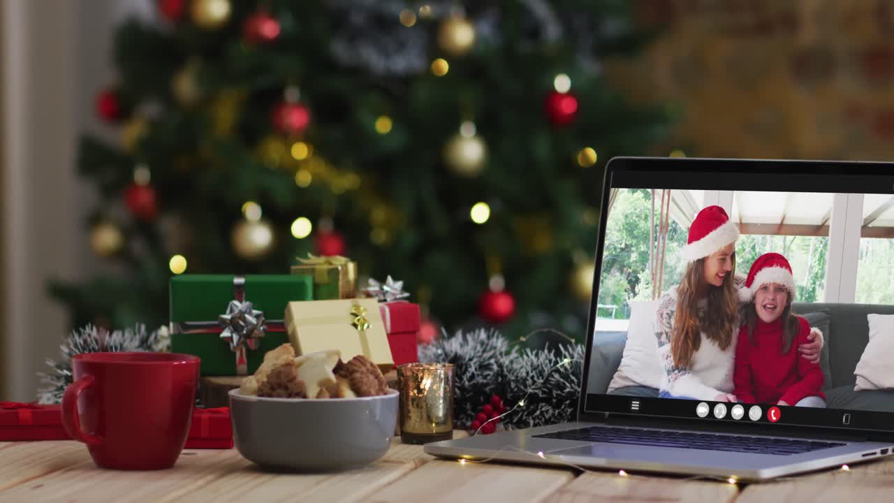 madre y hija felices en videollamada en computadora portátil, con decoraciones de navidad y árbol